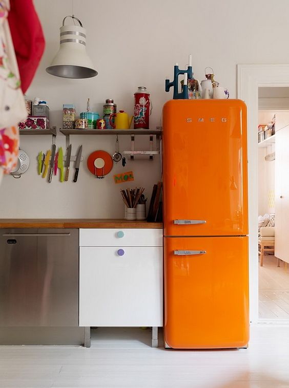 An eclectic kitchen with a bold orange Smeg fridge for a wow factor.