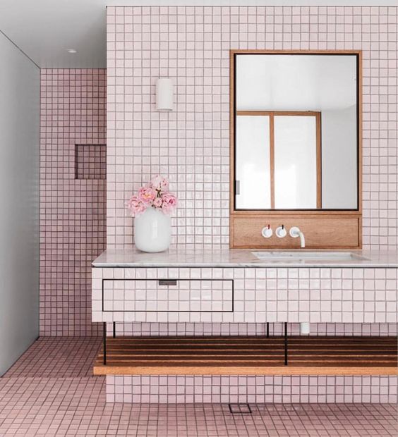 Glossy light pink tiles covering the floor and walls are calmed down with warm-colored wood and white touches.