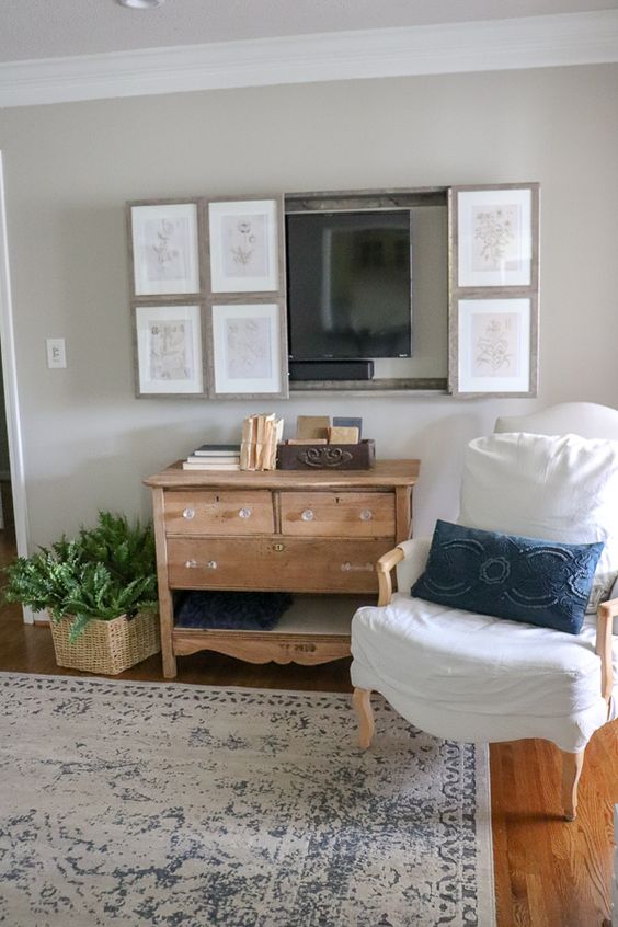 A farmhouse living room with vintage furniture, a reclaimed wooden vanity, a TV hidden behind a vintage poster gallery wall.