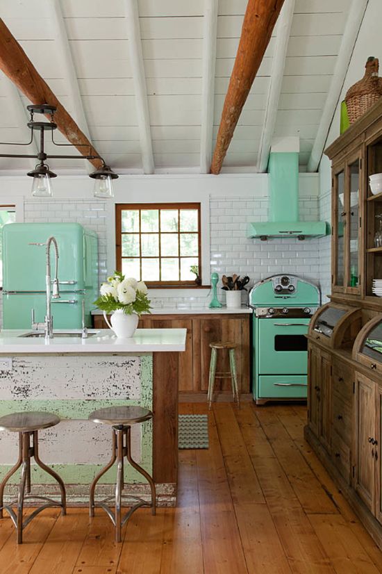 A rustic cottage kitchen is refreshed with a green fridge, cooker and a hood.