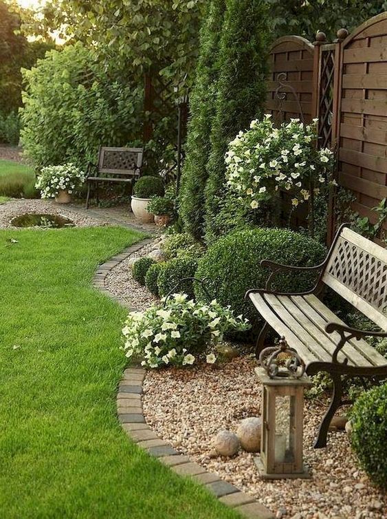 Brick edging is timeless, here it divides the lawn and the pebble covered garden bed with a bench.