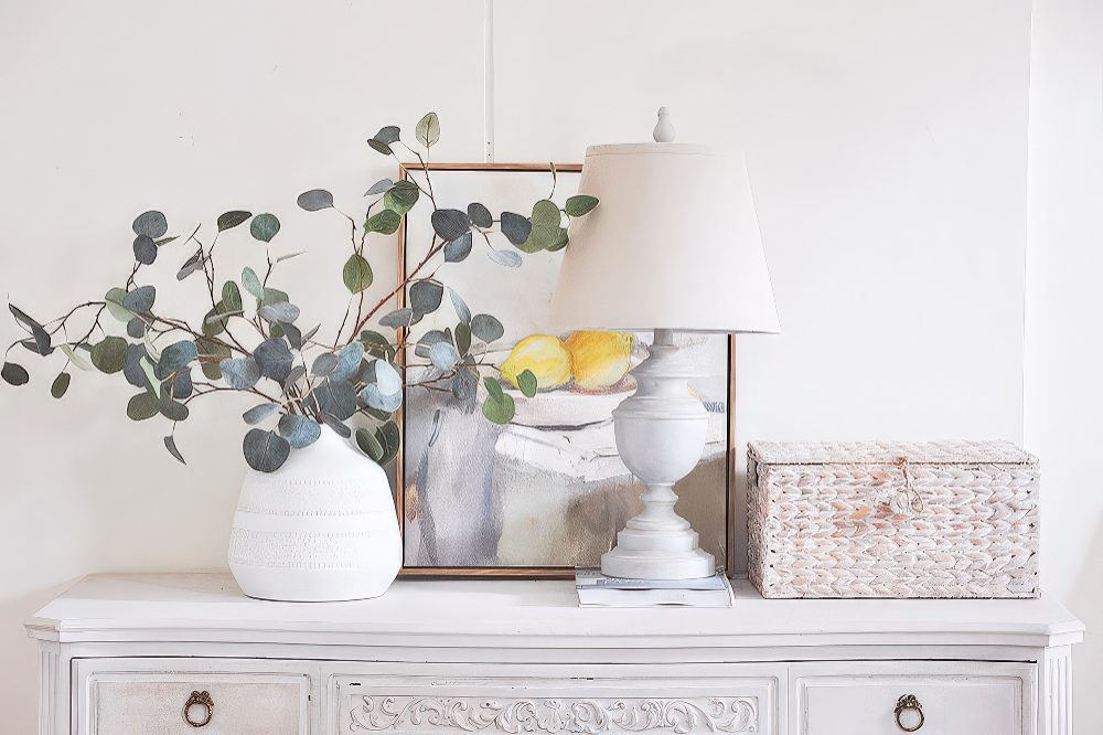 A lovely vintage-inspired interior in white, with a whitewashed woven box that hides a router, which is a very stylish idea.