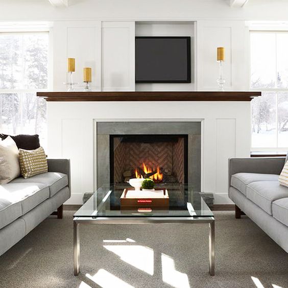 A modern neutral living room with a TV over the fireplace hidden with a sliding panel that is a cool and lovely solution.