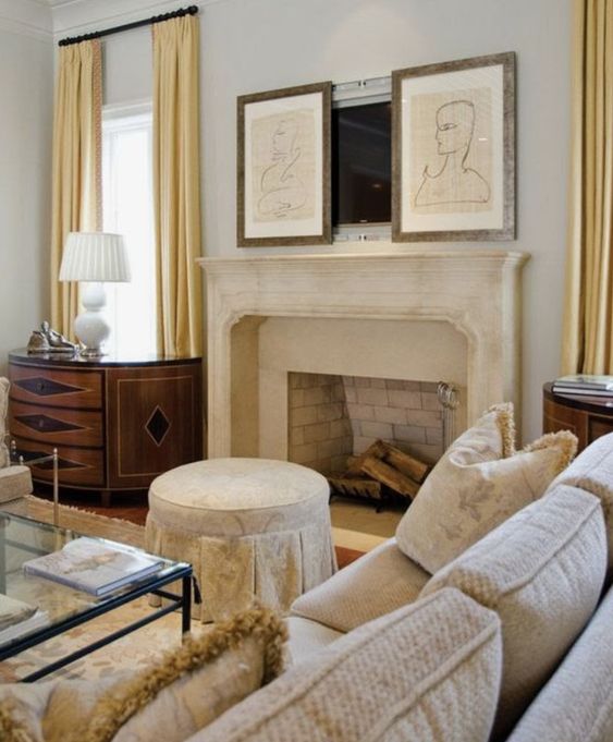 A refined modern living room done in neutrals, with a fireplace and an antique mantel, neutral sitting furniture, a TV hidden with two artworks.