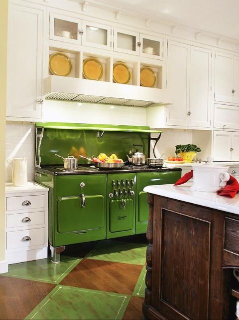 A traditional white kitchen with a green retro stove and a natural wood kitchen island.