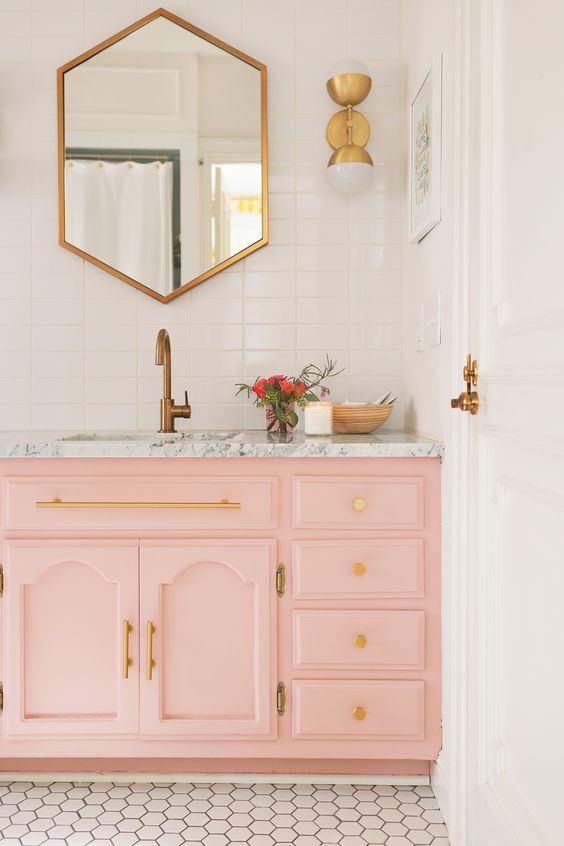 A light pink sink console with a marble top and gold handles and knobs are ideal for a glam bathroom look.