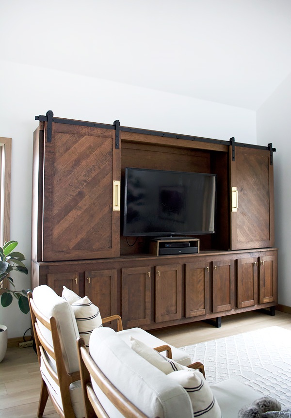 A beautiful and refined vintage dark-stained storage unit with sliding doors that hides a TV and makes a statement with its look.