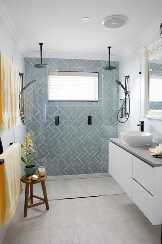 A chic tiny bathroom with light blue tiles, a floating white vanity with a cocnrete countertop, black fixtures and bold linens.