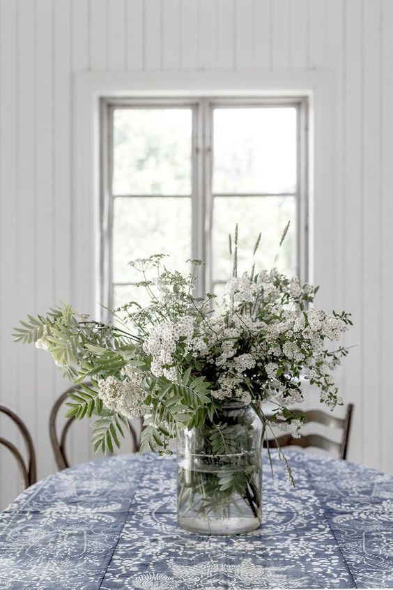 A clear vase with fresh white blooms and some leaves is a nice summer centerpiece or decoration.