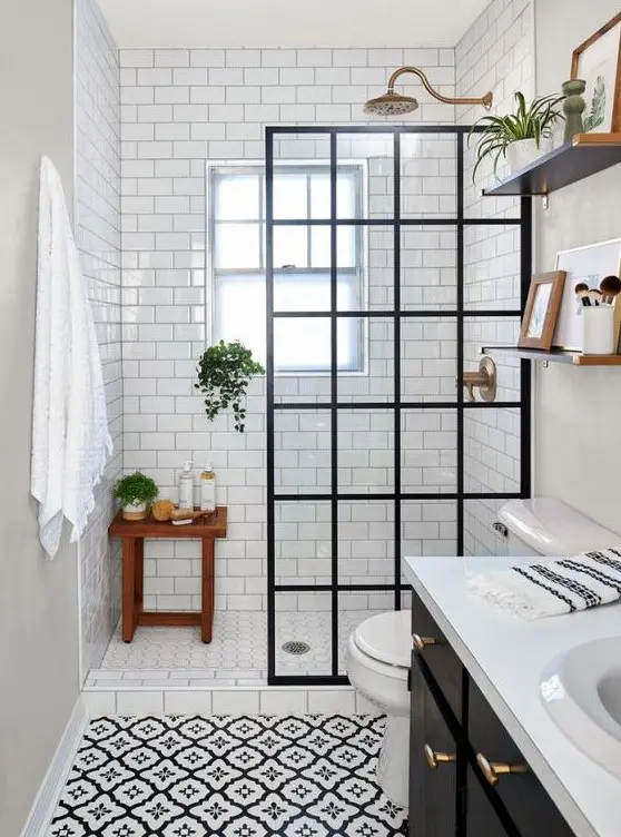 A contrasting black and white bathroom with white subway tiles and printed tiles, a black vanity, a framed screen and brass touches.