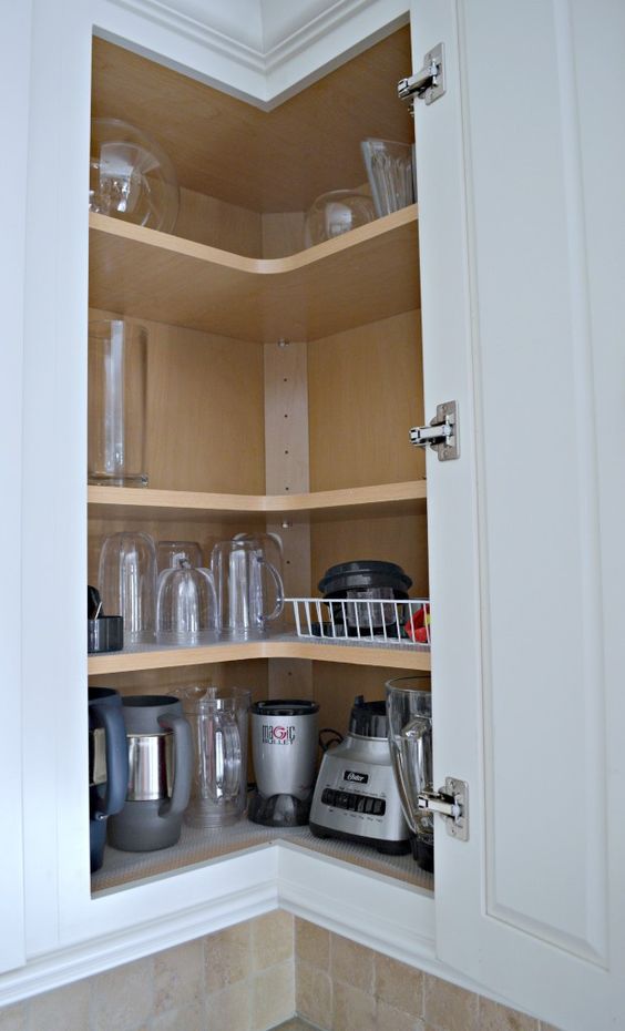 A corner cabinet with shelves that holds appliances and various mugs and glasses is a cool solution to save some space.