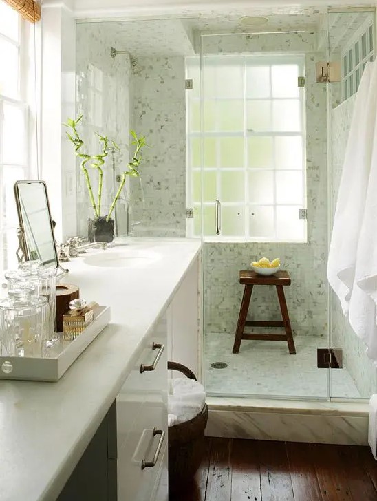 A cozy small bathroom with a large vanity and a built-in sink, a dark stained floor, a light green shower space.
