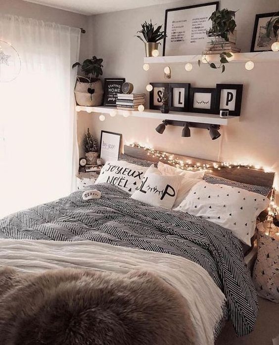 A cozy teen girl bedroom with a bed and printed bedding, shelves with lights and plants, books and magazines.