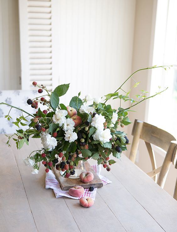 A fresh summer centerpiece or arrangement with white blooms, peaches and berries is a beautiful idea.