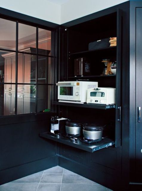 A large black cabinet holding all the appliances on retractable shelves helps to keep the kitchen in order and make it cooler.