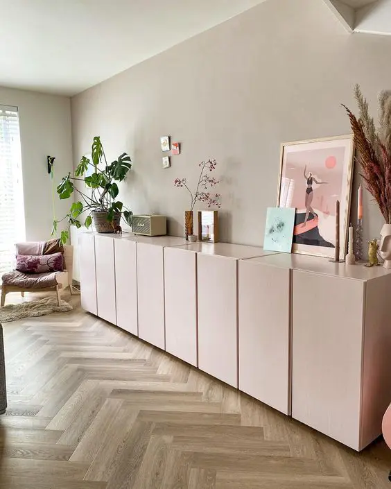 A large light pink sideboard composed of IKEA Metod cabinets, with beautiful decor and potted plants.