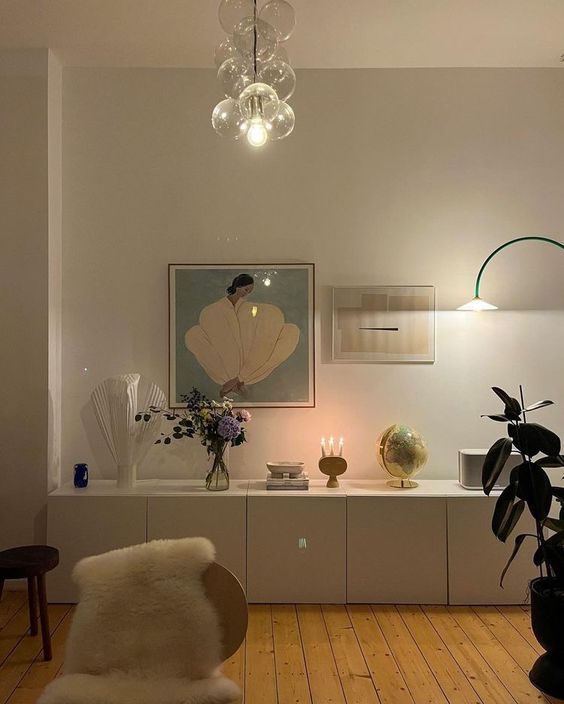 A large white sideboard built of IKEA Metod units, with blooms, decor, candles and lamps is amazing.