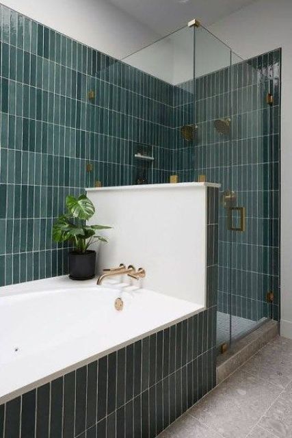 A lovely bathroom clad with green skinny tiles, with a half wall to divide the bathtub and shower space is amazing.