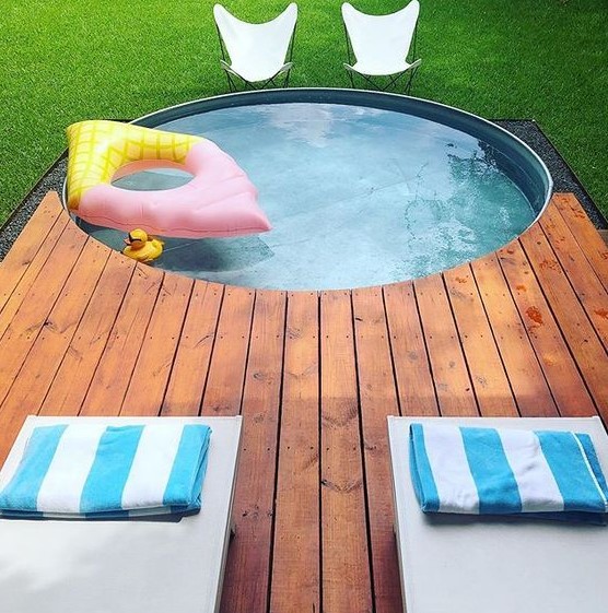 A lovely space with a stock tank pool and a deck, with loungers and butterfly chairs in front of the pool.