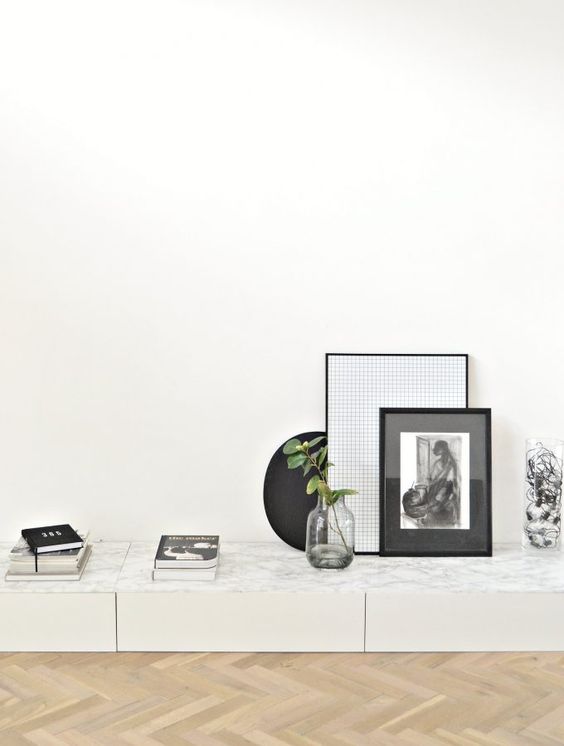 A low storage unit of IKEA Metod units, with a marble countertop, beautiful artwork and books.