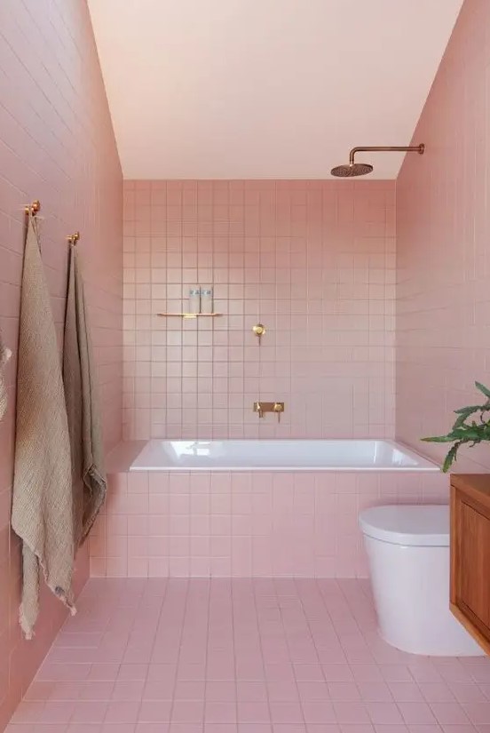 Gold fixtures add luxury to this modern glam bathroom clad in pink tiles. The chic combination of pink and gold creates an elegant atmosphere. Opt for metallic accents and bold colors for a stylish bathroom.