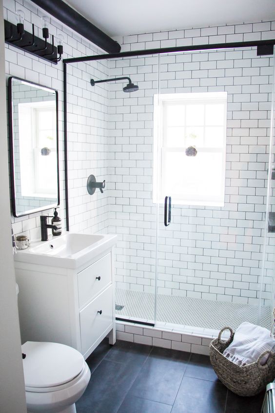 A modern monochromatic bahtroom with white subway tiles and black ones, a white vanity and black fixtures here and there.