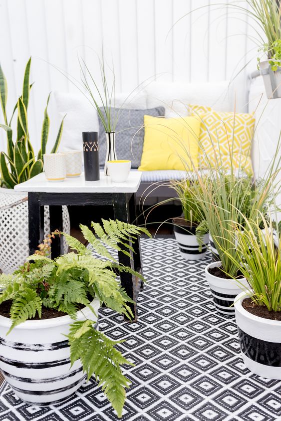 A monochromatic balcony with printed textiles, potted greenery and succulents and simple and stylish furniture.