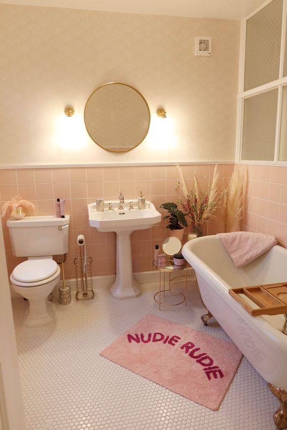 A neutral and blush bathroom with white vintage-style appliances, pink textiles and some pampas grass.