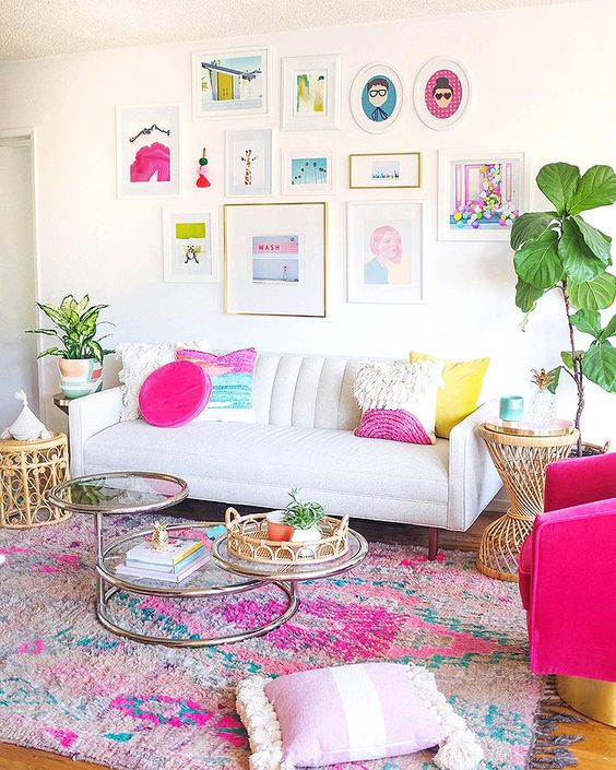 A neutral living room with colorful pillows, a bright printed rug, a colorful gallery wlal and potted greenery here.