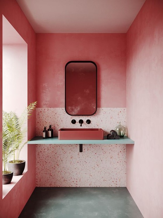 A pink bathroom with bright walls, terrazzo elements, a pink sink and black touches for some drama.