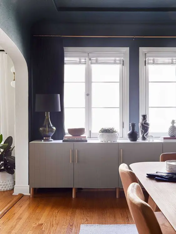 A pretty long sideboard of IKEA Metod cabinets, with grey planked doors, wtih vases, decor and potted plants.