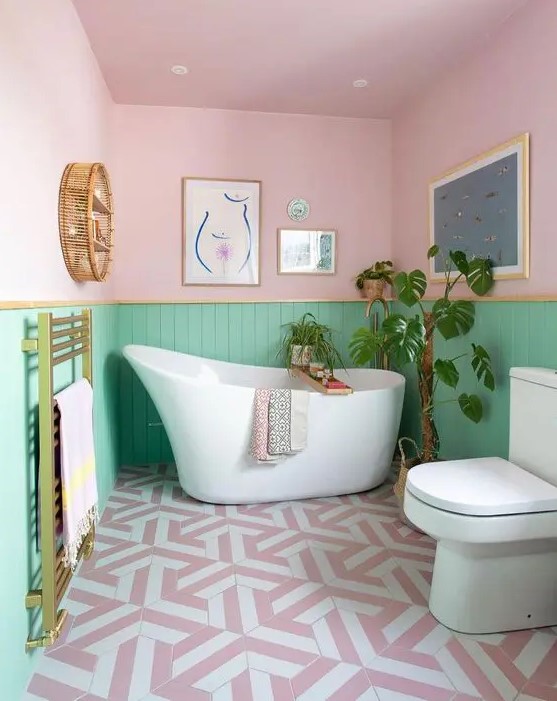 Gold touches bring elegance to this pretty pastel bathroom with pink and green paneled walls. White appliances and lovely artworks complete the fun design. Opt for metallic accents and charming decor to create a playful bathroom space.