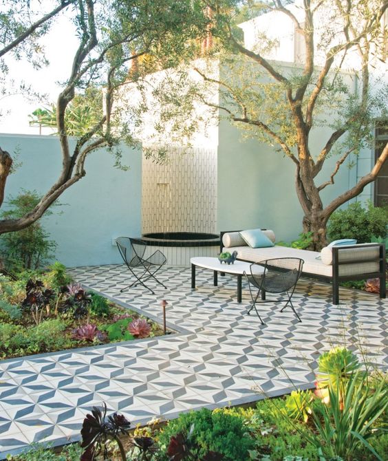 A refined modern terrace with a Mediterranean feel with greenery and succulents, a tiled deck, metal furniture and a fountain.