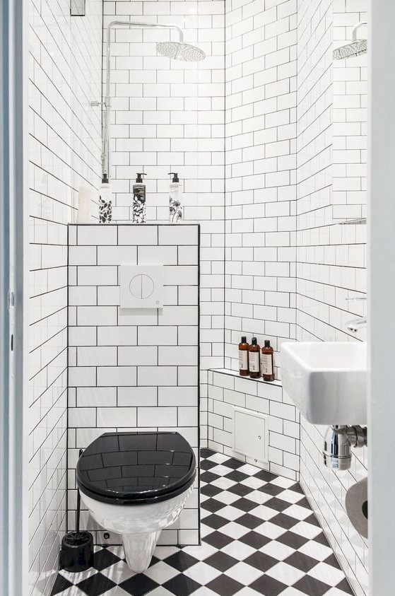 A retro-inspired black and white bathroom with a shower space, a mosaic tile floor and a half wall.