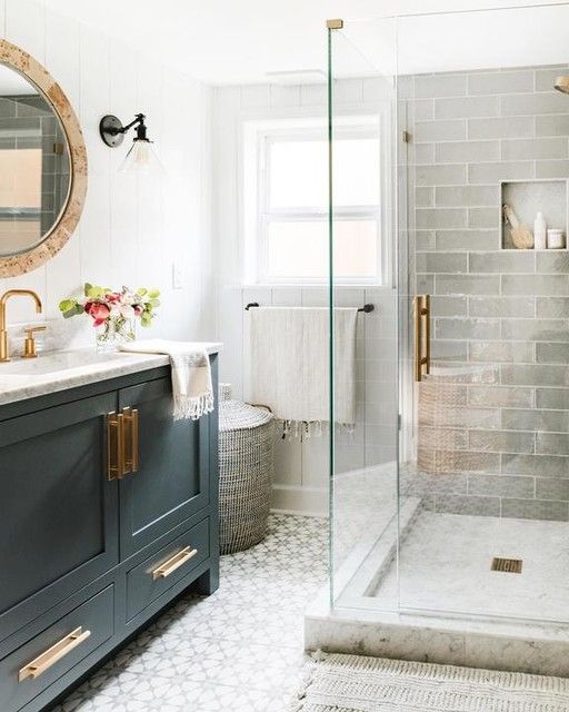 A small bathroom with grey long tiles and printed ones on the floor, a graphite grey vanity, touches of gold and a marble countertop.