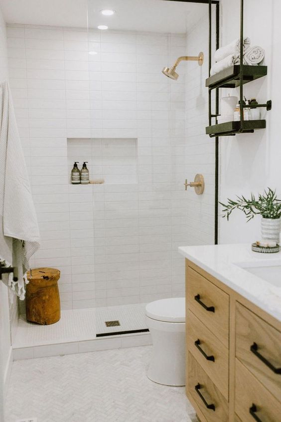 A small contemporary bathroom clad with white and mother of pearl tiles, a neutral vanity, a wooden stool and touches of black.