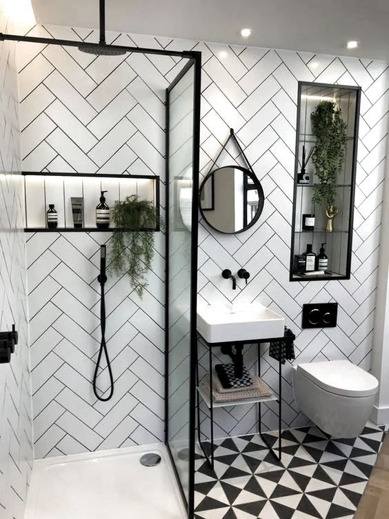 A small contemporary bathroom with herringbone clad tile walls, a printed floor, a small sink and a shower with a glass divider.