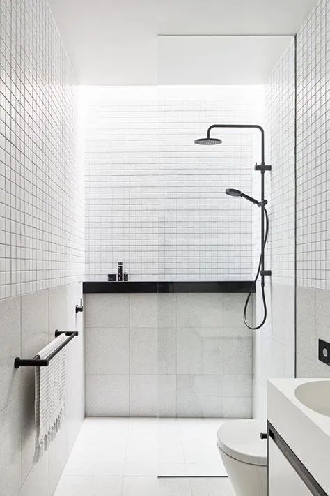 A small minimalist bathroom in black and white, with white small and large scale tiles, black fixtures and other touches.
