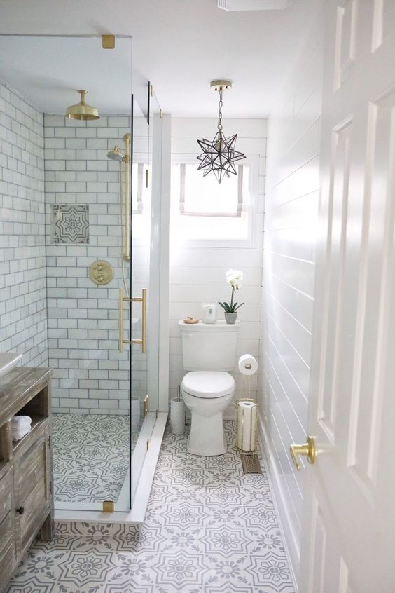 A small peaceful bathroom with white subway tiles, pritned floor, touches of gold and a star-shaped pendant lamp.
