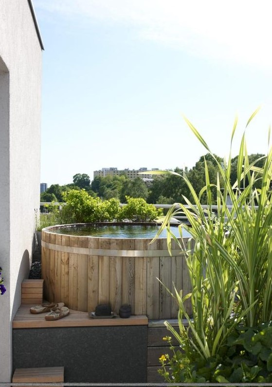 A small pool space with a stock tank pool clad with wood and with wooden ladders, with growing grasses is a lovely nook to refresh yourself.