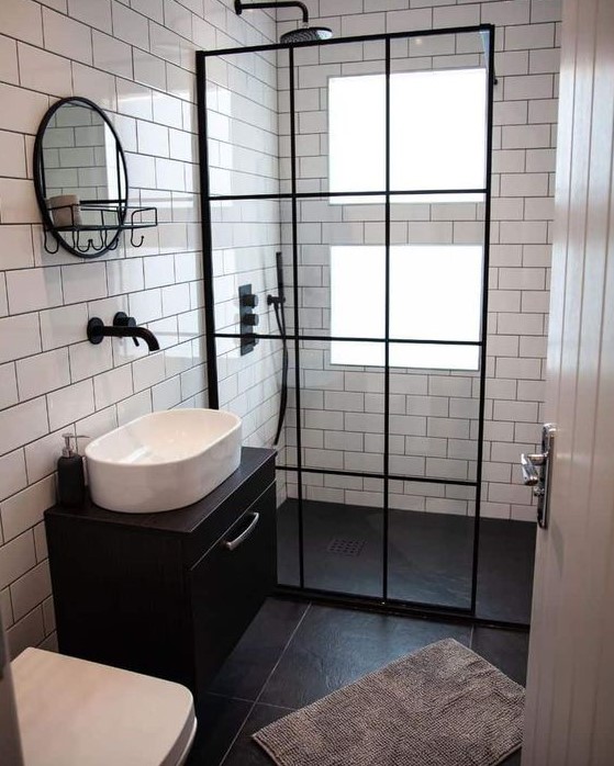 A tiny bathroom features contrasting white and black tiles and windows in the shower. A black floating vanity adds modern elegance. Black accents complete the stylish design.