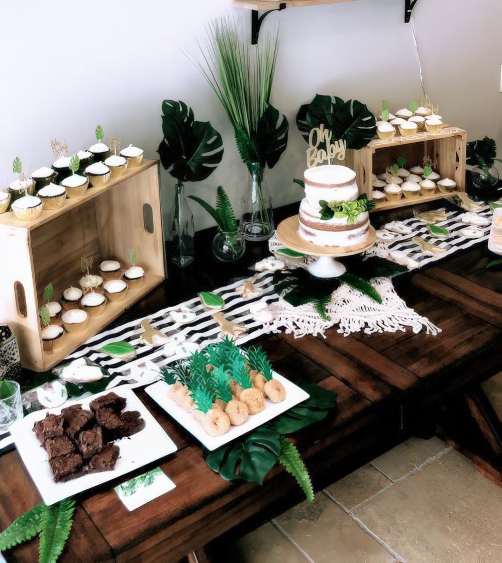 A tropical dessert table done in black and white with touches of green, with stripes, tropical leaves and delicious sweets.