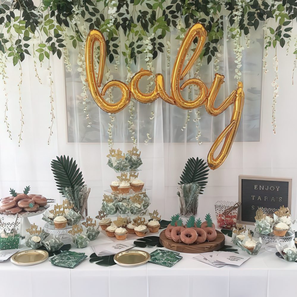 A tropical dessert table with gold calligraphy balloons, tropical greenery, a sign and lots of delicious sweets.