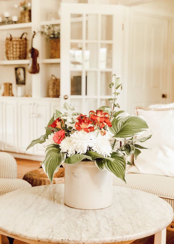 A white metal bucket with red and white blooms and oversized leaves for a simple and cool summer bouquet.