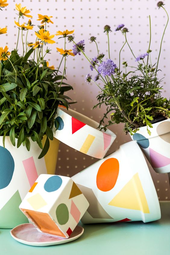 An arrangement of colorful print pots attached to each other and with bright summer blooms is lovely.