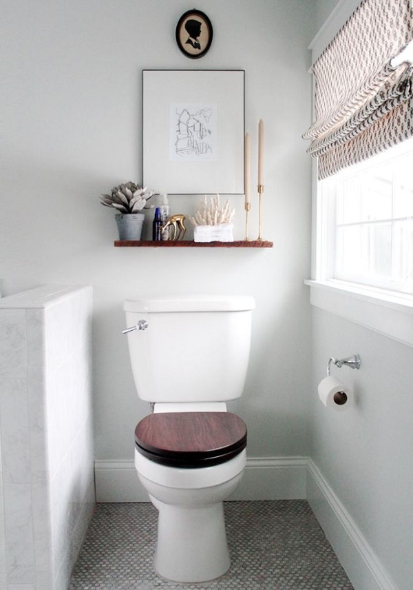 A small neutral bathroom with a half wall that divides the toilet from the rest of the space and neutral shades.