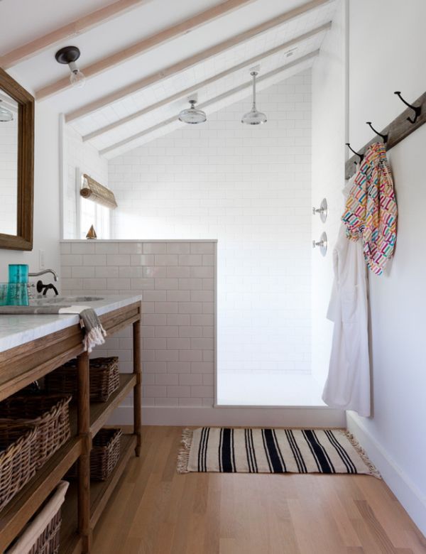 A neutral farmhouse bathroom clad with white subway tules and a pony wall that separates the shower from the rest of the space.