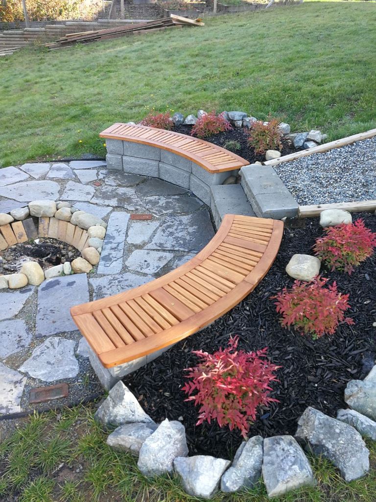 This lovely space around the fire pit is styled with a curved bench and a stone patio.