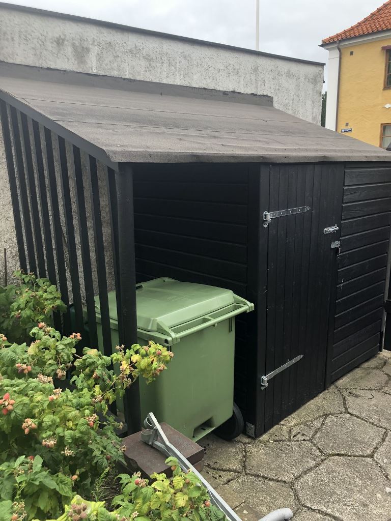 This small garden shed isn't only a storage unit but is also a cover for the trash can.