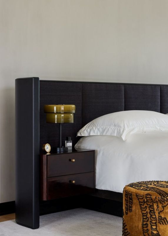 The upholstered bed features a masculine wingback headboard and a floating nightstand attached to the headboard.